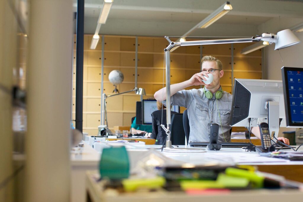 young-man-drinking-coffee-at-office-desk-3926DV7.jpg